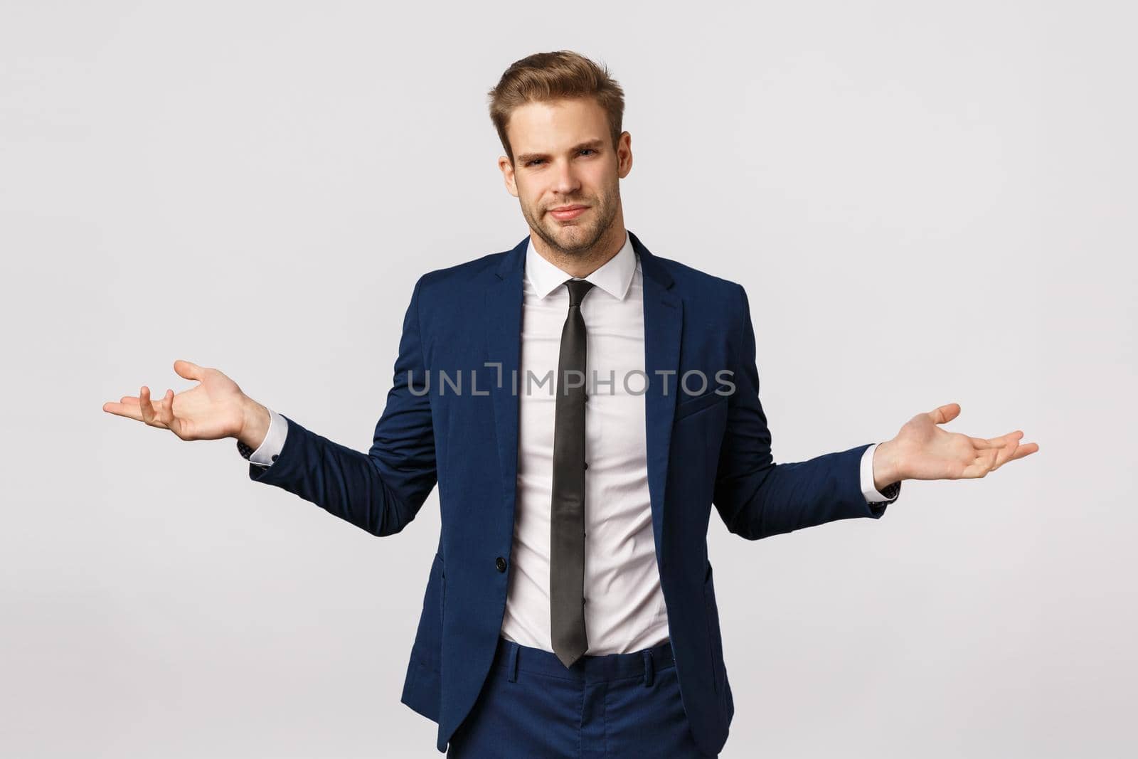 I dont know. Unsure and puzzled handsome businessman with bristle, blond haircut, wear suit, spread hands sideways and shrugging uncertain, have doubts about client, frowning perplexed.