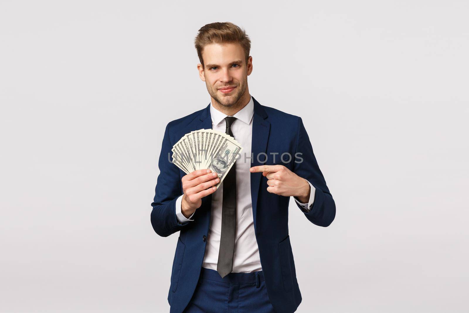 Check this out, how success looks like. Handsome businessman with cash in hands, pointing money and smiling confident, bragging, discuss how manage business, starting own company by Benzoix