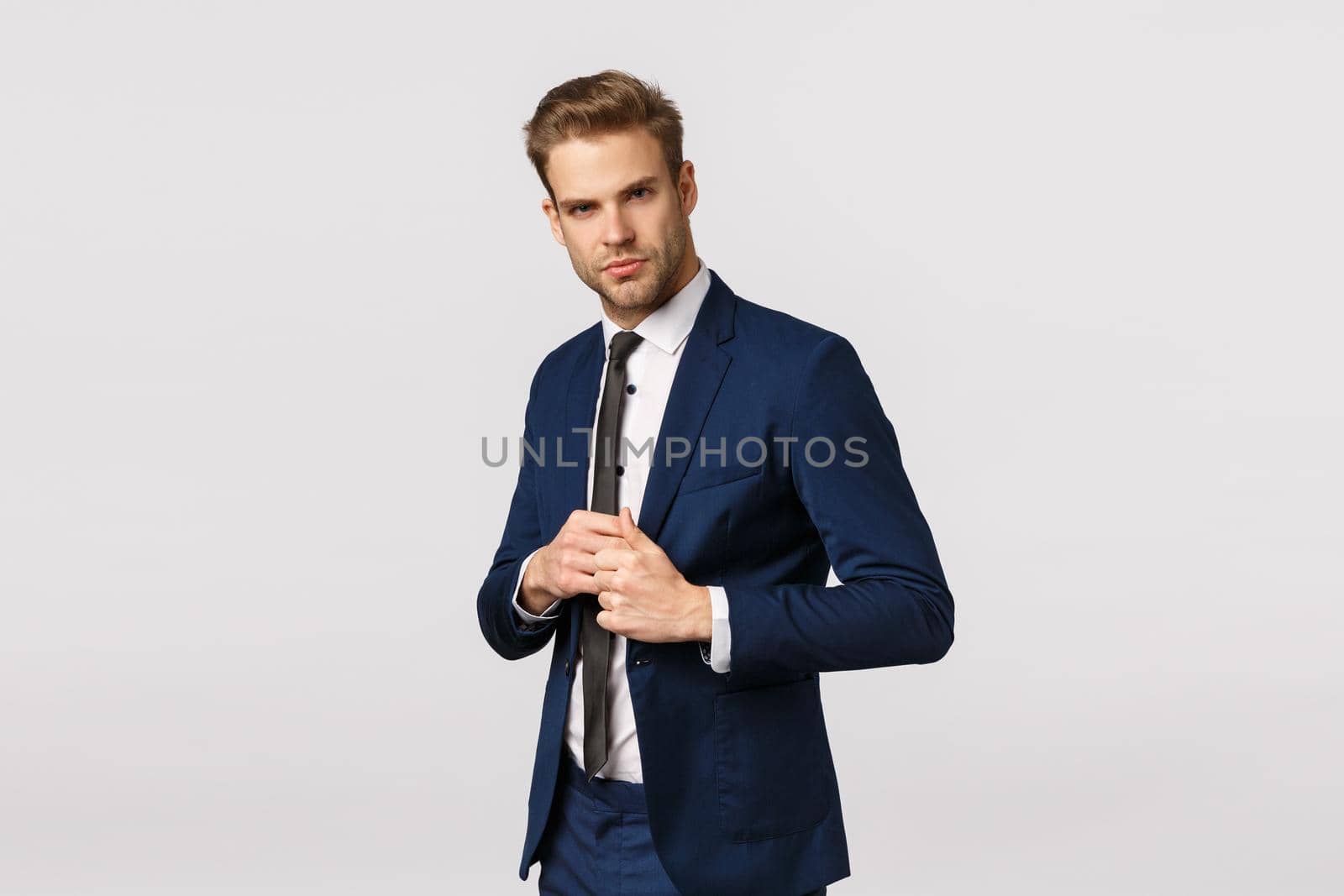 Determined, confident businessman in suit, fixing jacket, looking sassy and pleased camera, signed good deal, feeling lucky and self-assured, manage business, standing white background by Benzoix