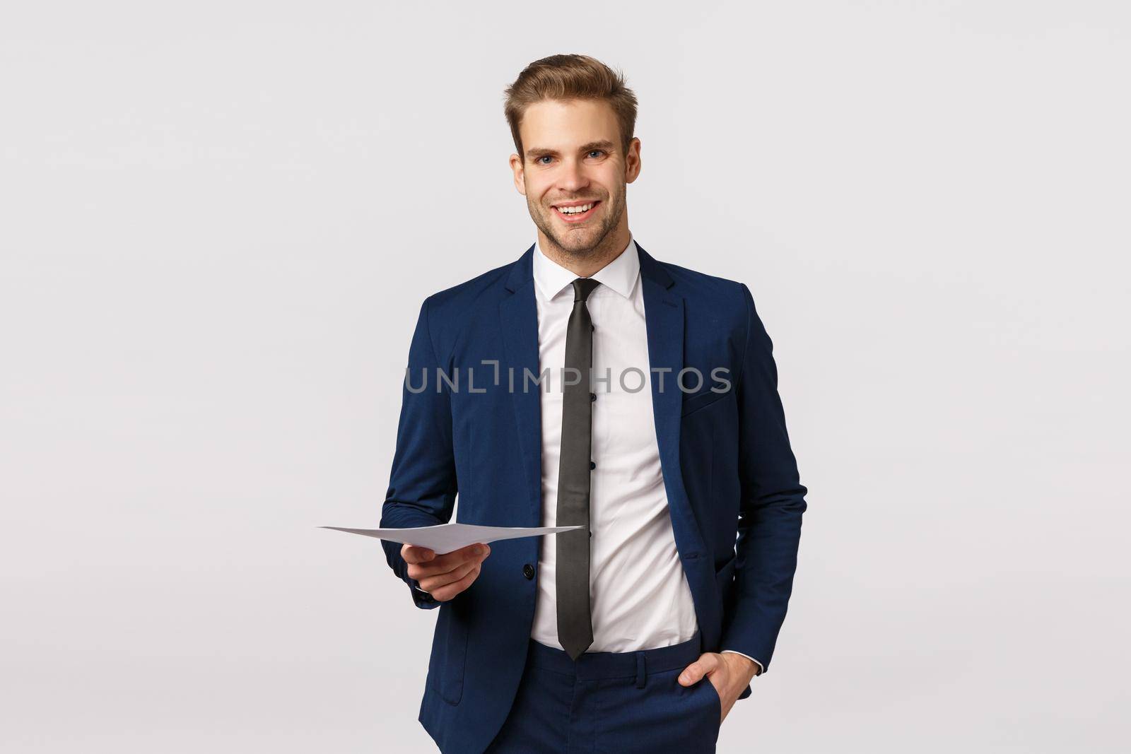 Handsome young wealthy businessman in classic suit, holding papers and smiling, having business meeting discuss finance staff with partners, manage enterprise, standing white background.