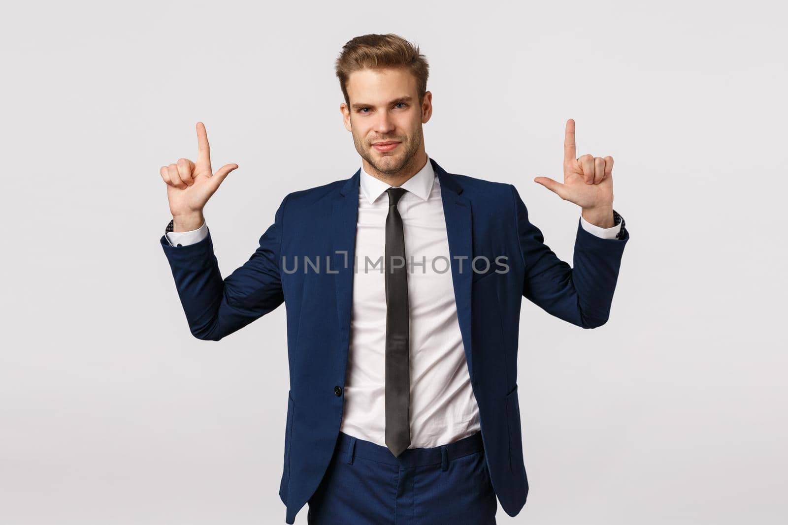 Confidence, business and corporate concept. Attractive young bearded businessman, man in suit, pointing up and smiling camera with assertive look, know what you searching, give advice by Benzoix