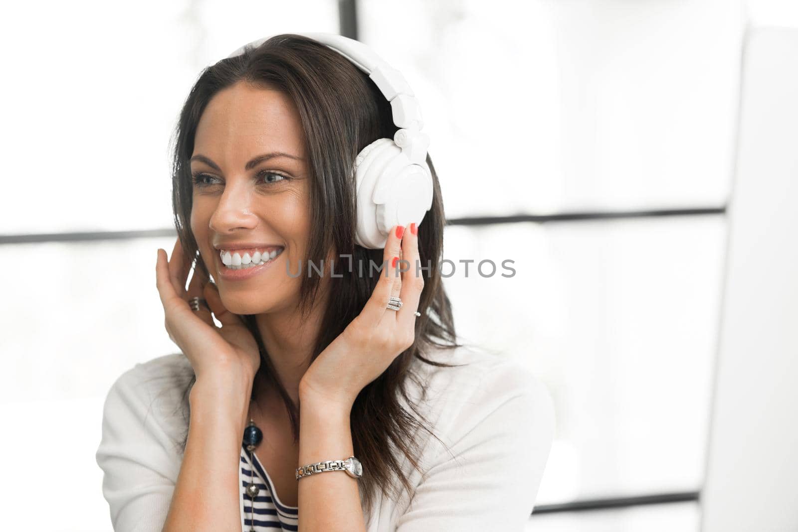 Portrait of pretty brunette woman wearing headphones in office
