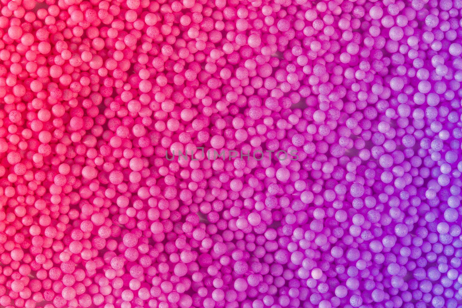 Many pink and violet little balls for children playground. Cosmetics powder. Candy sprinkles. Top view. Trendy absract background or backplate for your design. Color 2022