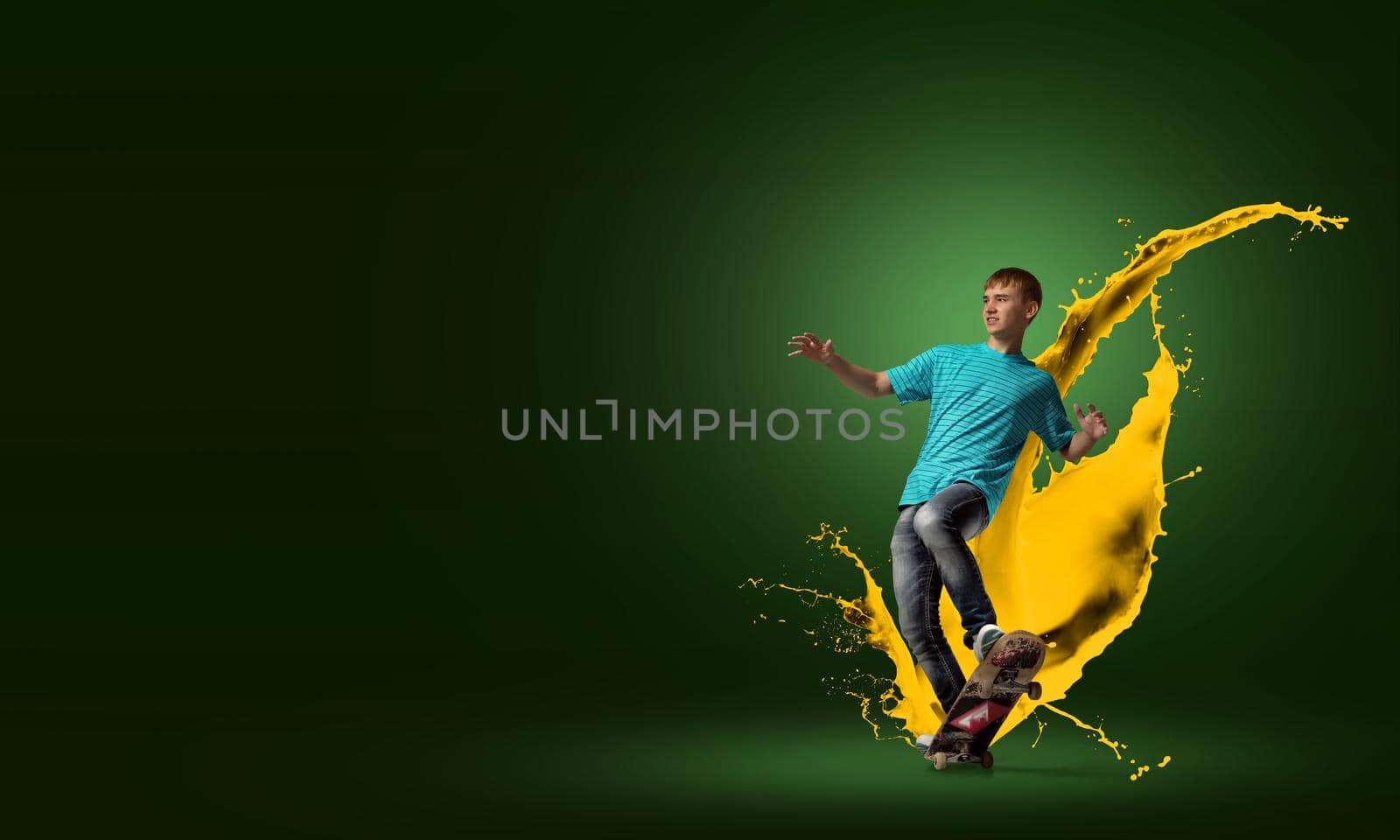 Young guy riding skateboard and paint splashes from under wheels