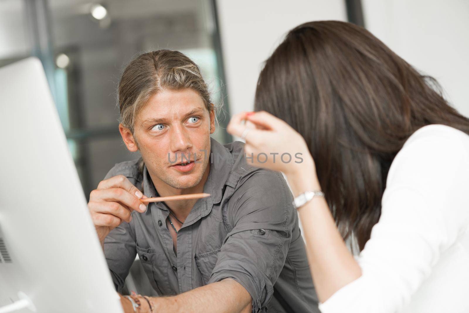 Young coworkers working together and discussing points while using computer