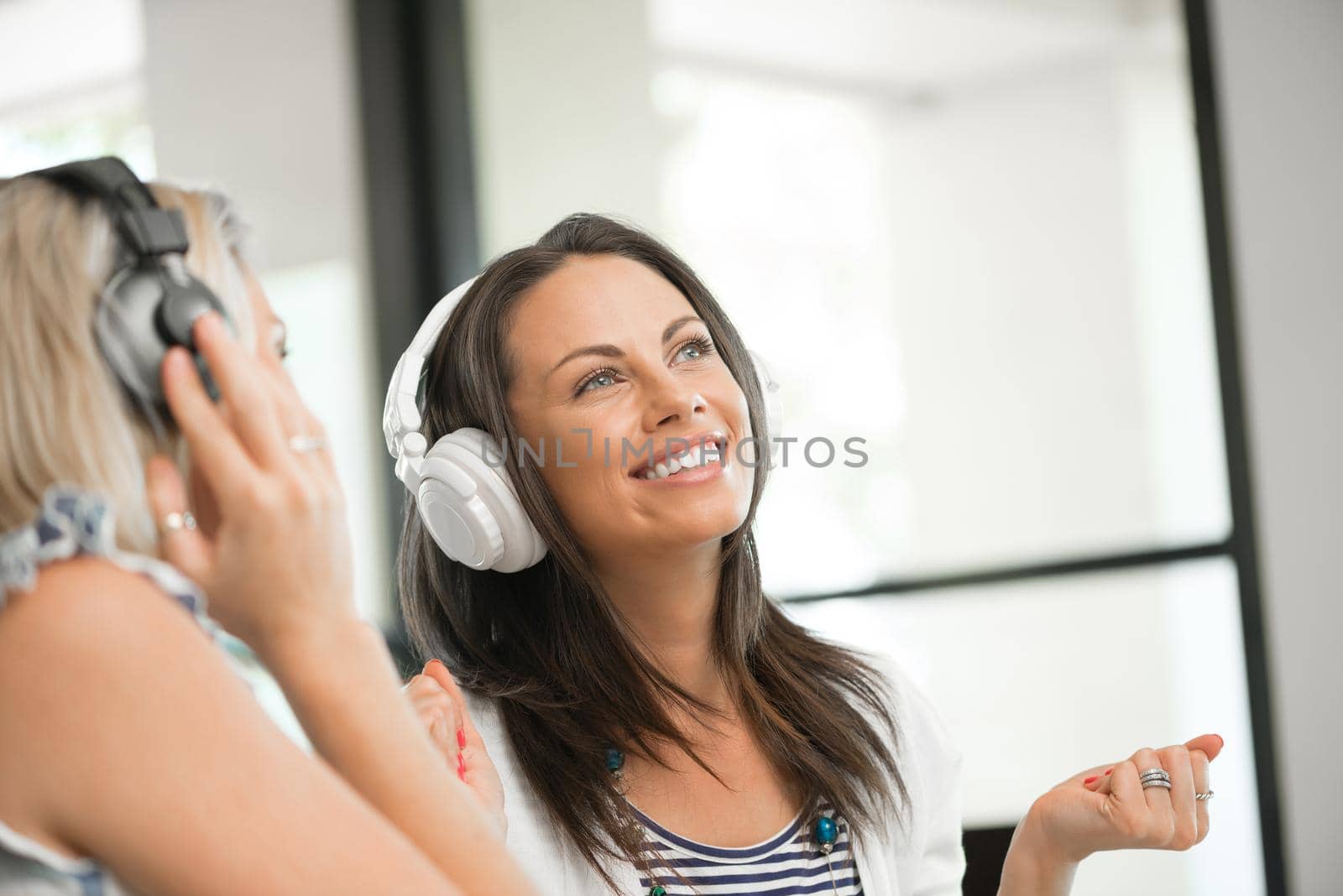 Two pretty women in headphones sitting at desk in office