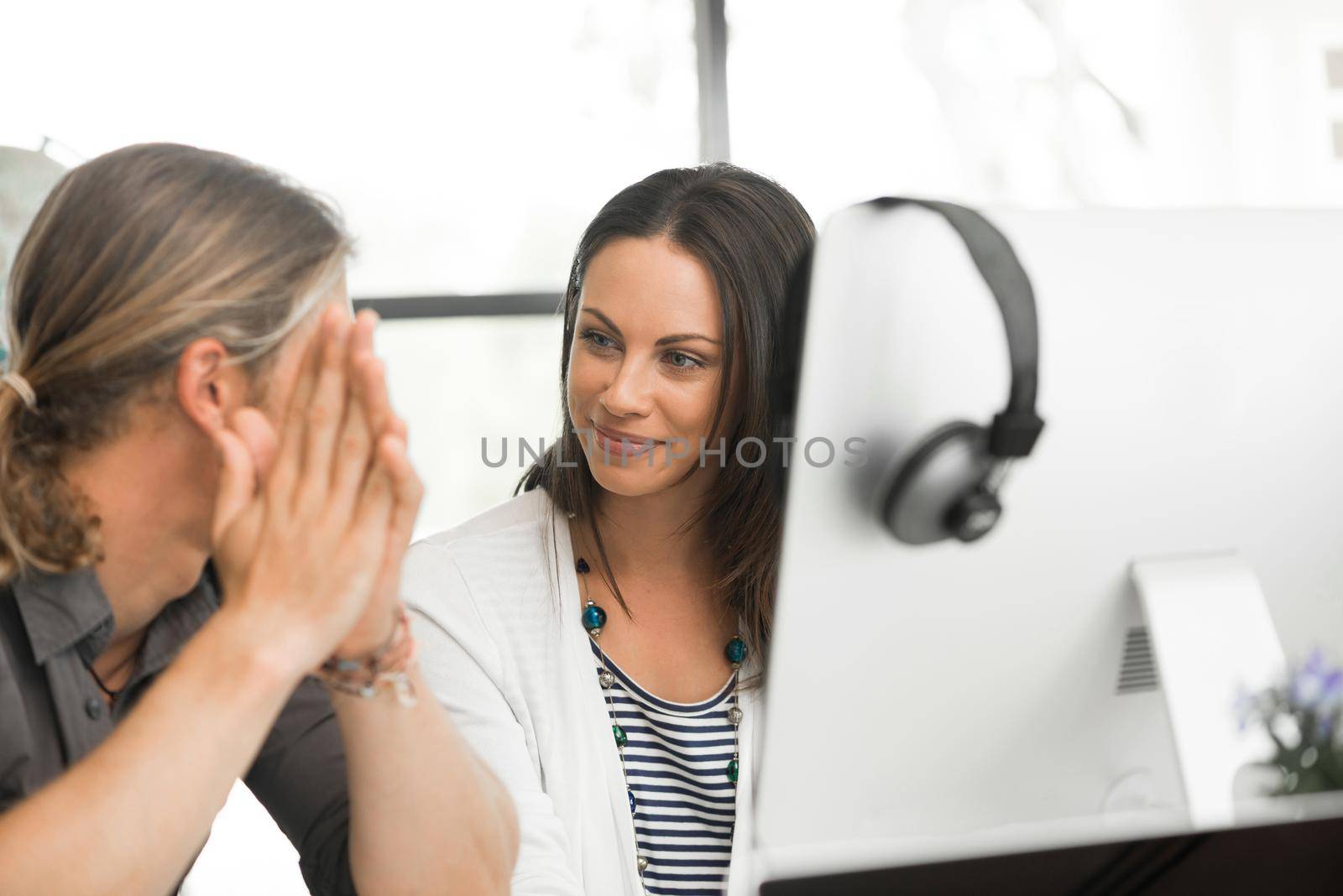 Young coworkers working together and discussing points while using computer