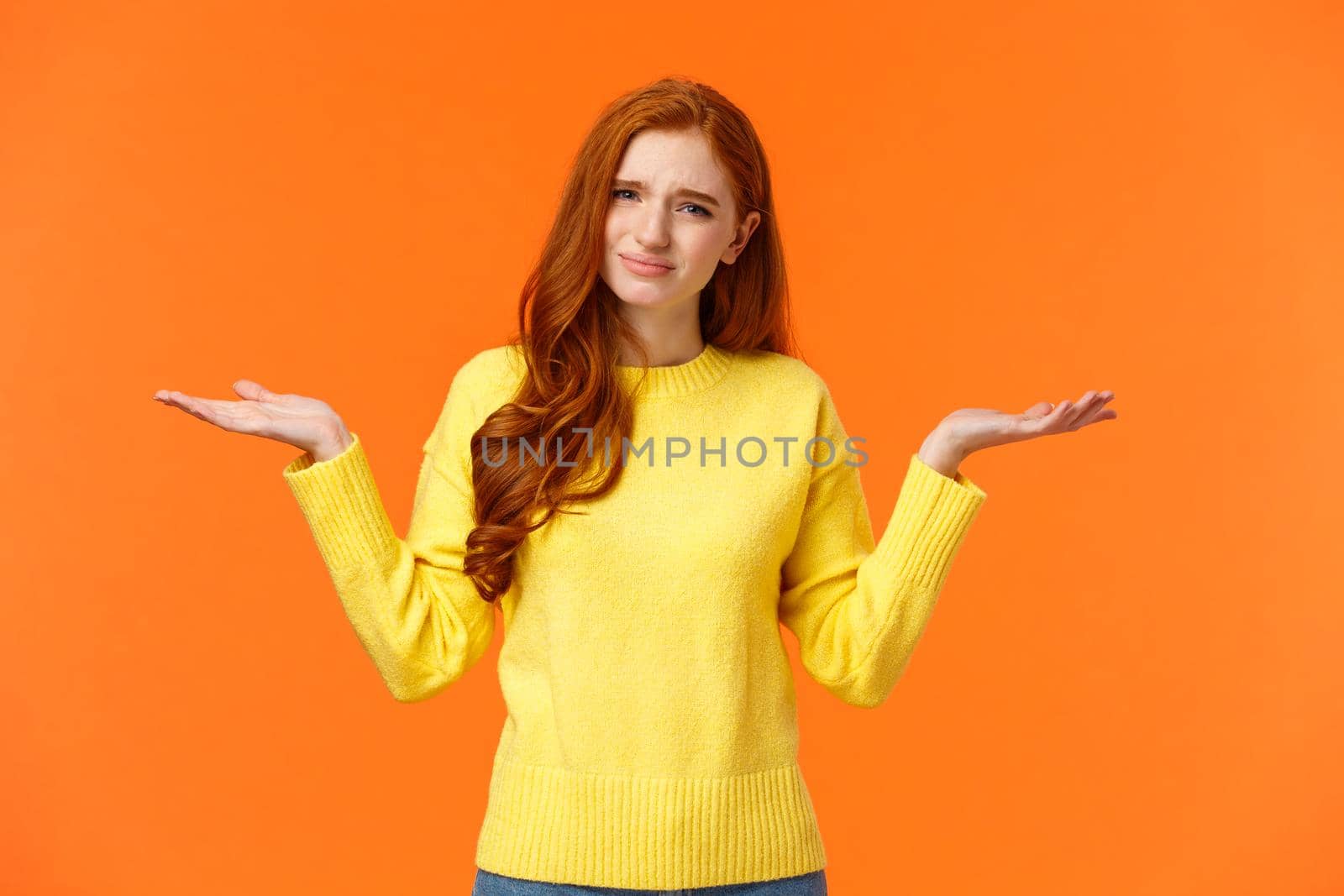 Girl hearing ridiculous stupid question. Careless and unbothered cute redhead woman in yellow sweater, shrugging with hands raised sideways, frowning grimacing indecisive, feeling confused by Benzoix