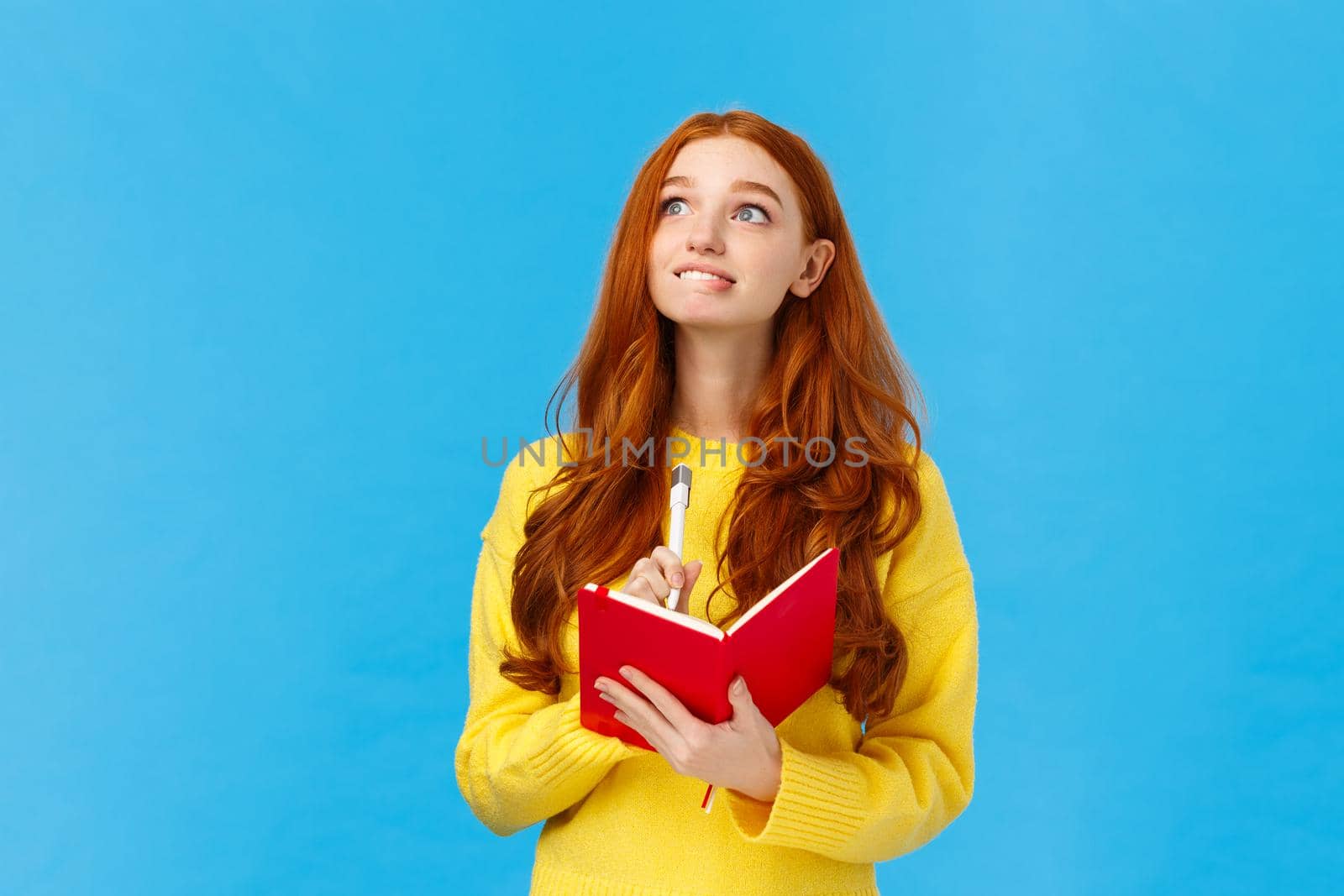 Girl full of hopes and aspirations writing down wishes in notebook. Inspired and creative attractive redhead woman looking upper left corner dreamy and hopeful, hold pen and diary, smiling.