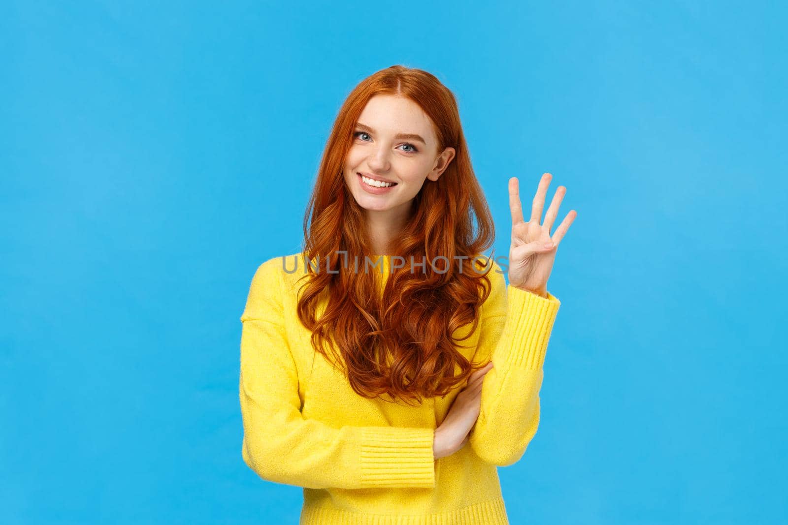Consumer, shopping and fashion concept. Attractive ginger girl, redhead woman making reservetion, place order four products, smiling and gazing friendly camera, counting with fingers, blue background.