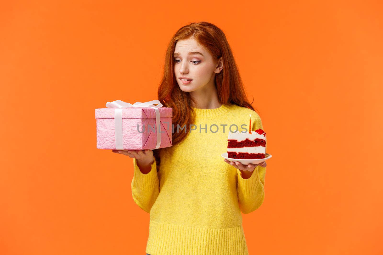 Celebration, presents and holidays concept. Cute redhead girl looking with temptation, desire at gift box, holding wrapped present, piece of delicious b-day cake, birthday girl want unwrap surprise.