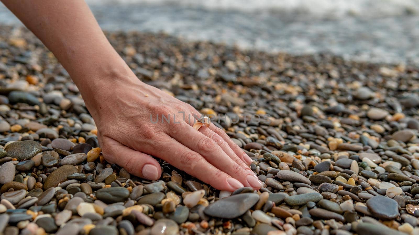 Ring on the sea, on the hand put on, a beautiful girl's hand overlooking the sea on the beach stony, summer