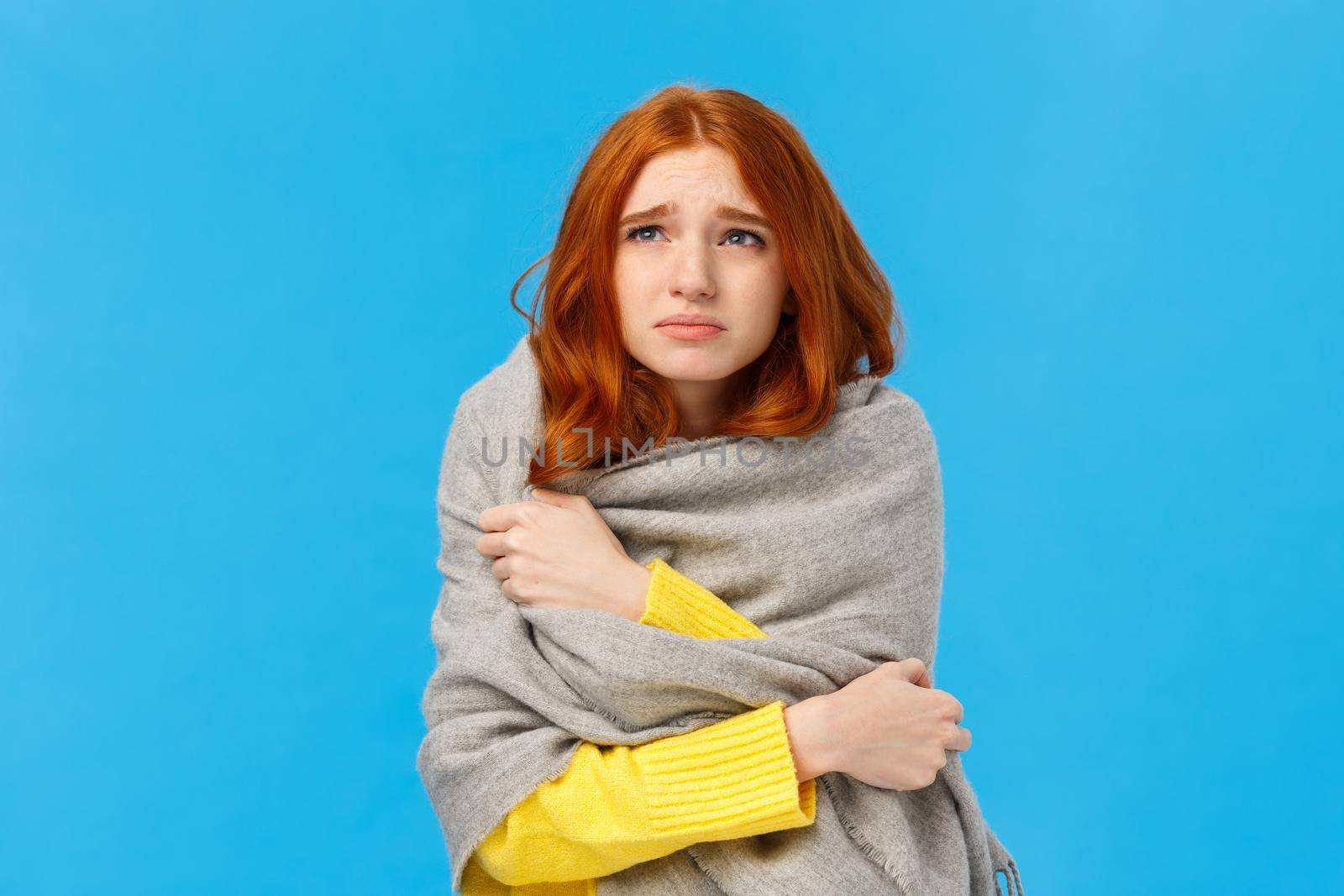 Girl sitting dormitory with broken heater, wrapping herself with warm scarf, looking upset and unwell upper left corner, grimacing suffer discomfort low temprature, catching cold, blue background.