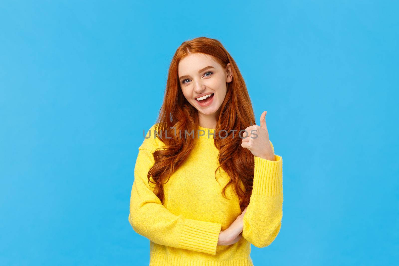 Wonderful idea. Supportive cute redhead girlfriend encourage you try, approve good choice, smiling pleased, nod approval and showing thumb-up like gesture, stand blue background by Benzoix