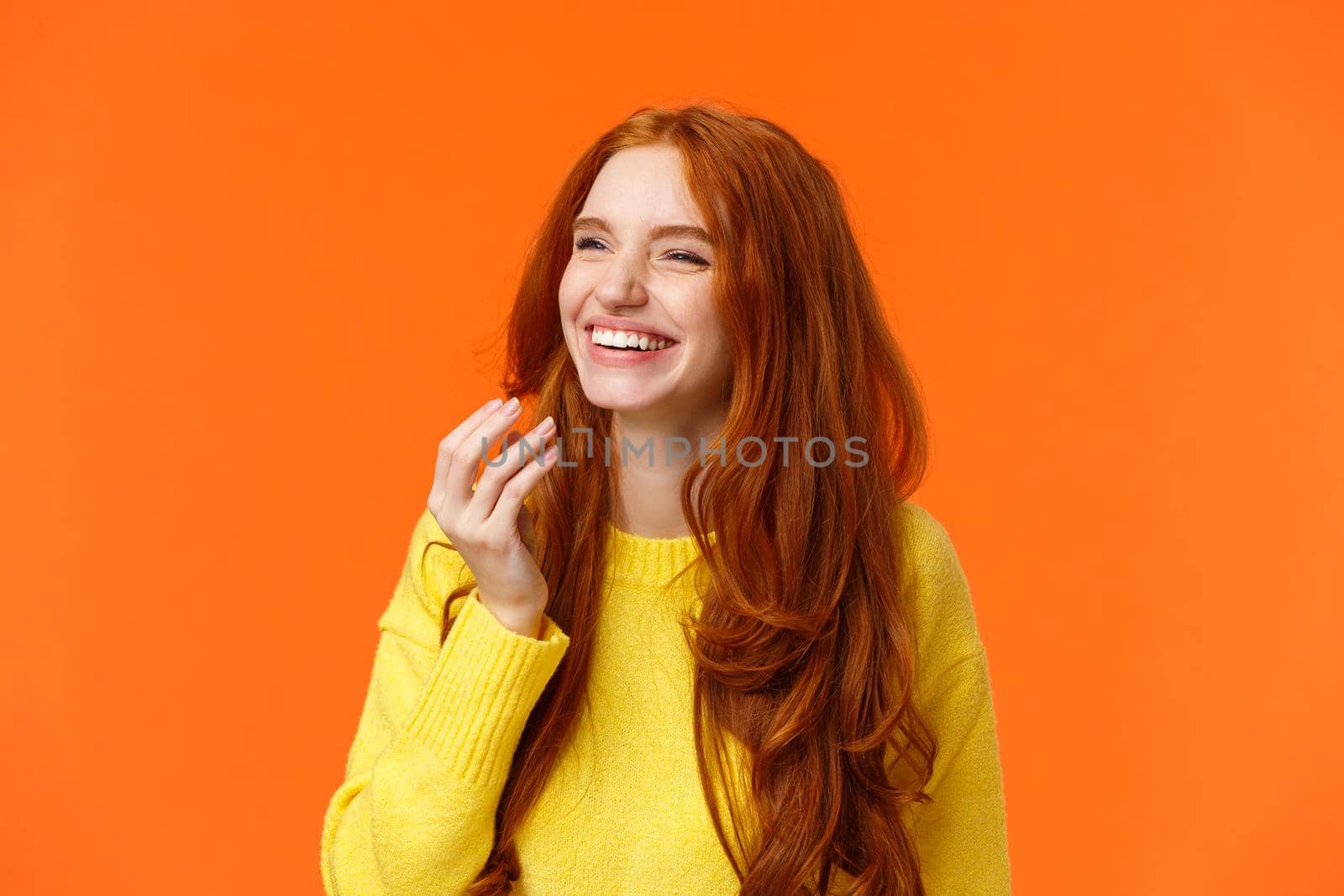 Emotions, holidays and positivity concept. Carefree modern hipster redhead girl having fun spend time with friends, laughing, smiling joyfully, giggle watching funny comedy movie, orange background.
