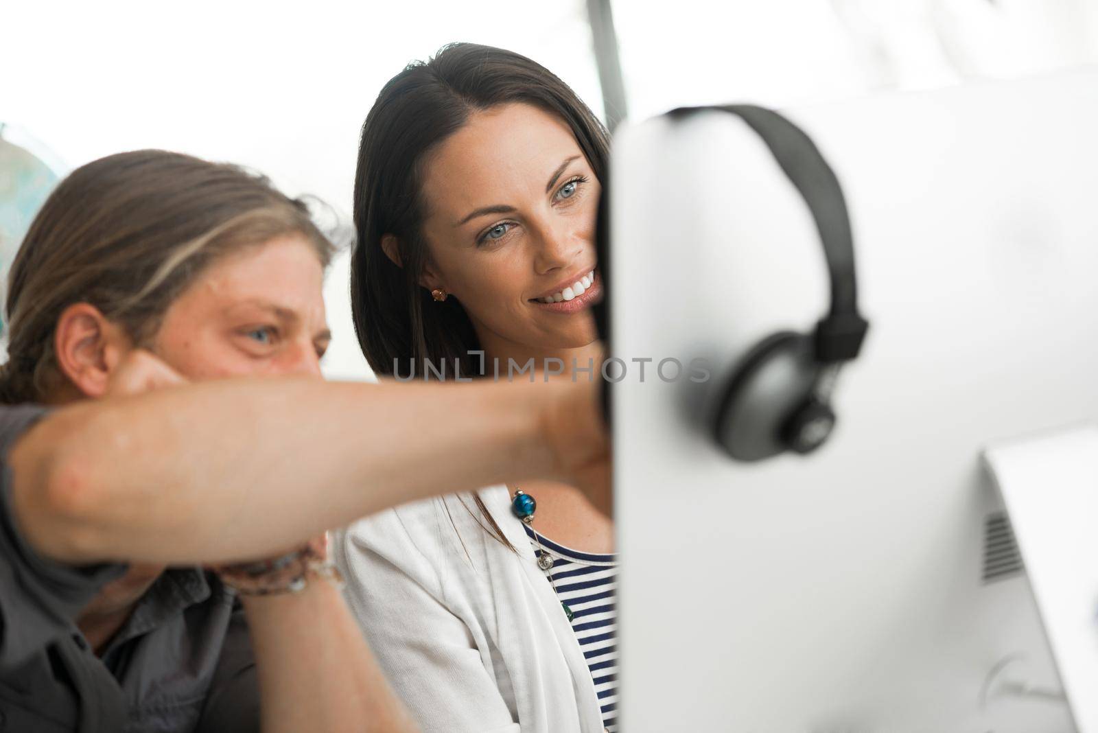 Young coworkers working together and discussing points while using computer