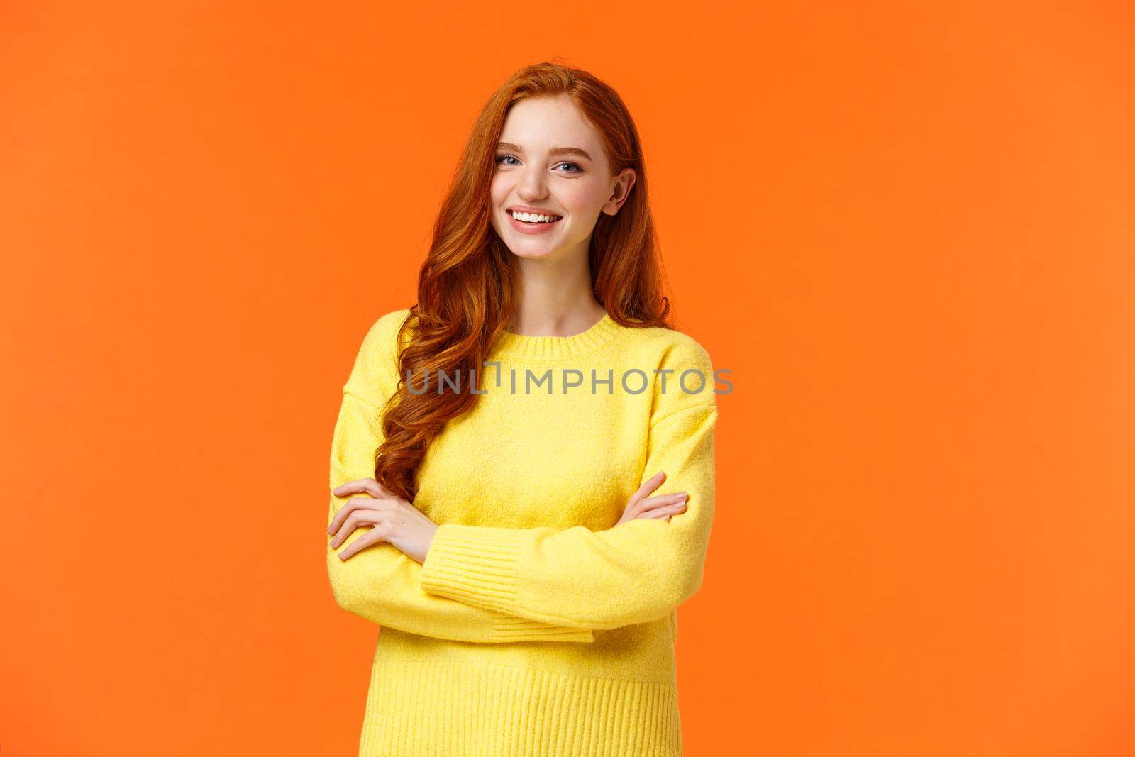 Business, e-commerce and people concept. Modern student, redhead girl learn IT, digital design in college, cross arms over chest with confident, assertive posture, smiling happy, orange background.