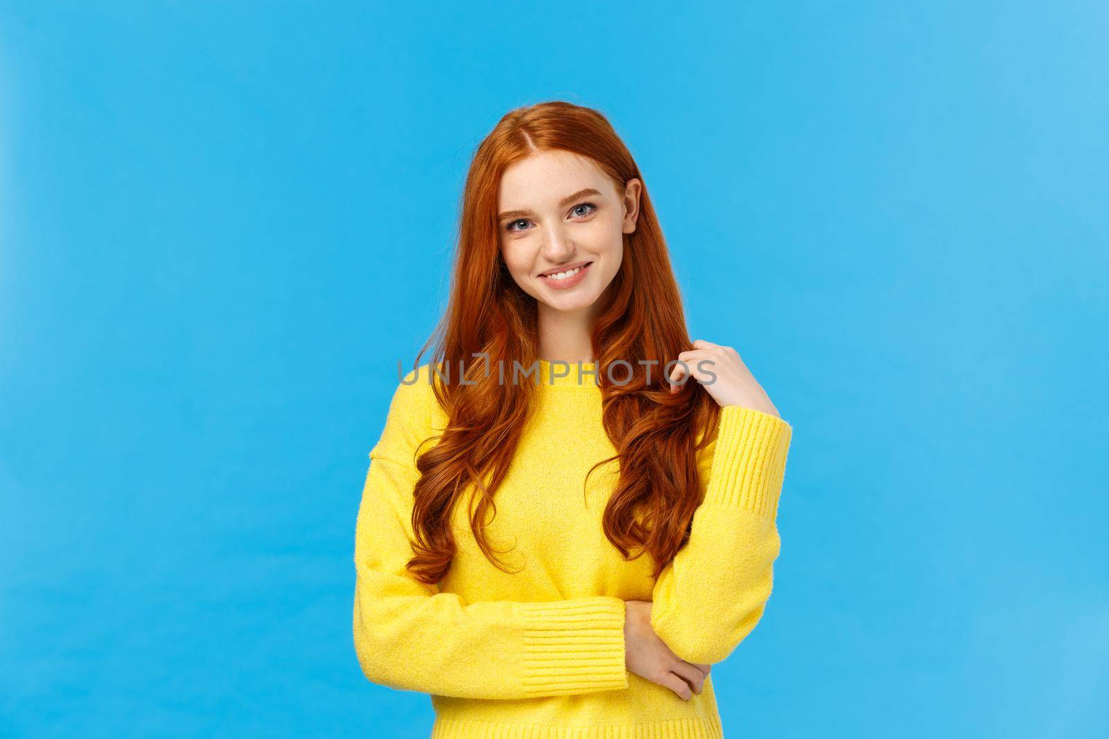 Waist-up shot attractive flirty redhead modern girl millennial in yellow sweater, playing with hair and smiling lovely with entertained, curious expression, looking camera having conversation by Benzoix