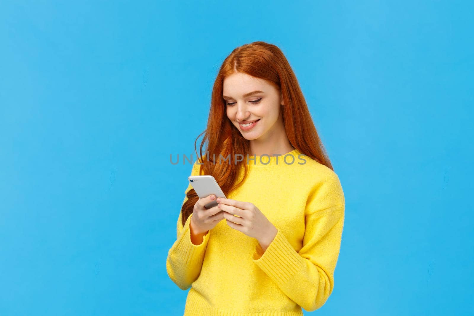 Conversation, messaging and people concept. Redhead cute carefree girl enjoy browsing online, picking new dress internet store, shopping using smartphone, smiling found excellent choice, order.
