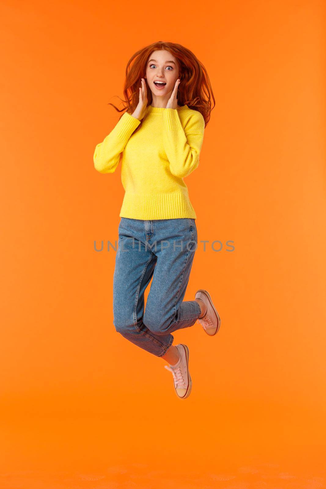Emotions, holidays and people concept. Full-length vertical portrait cute and silly jumping redhead female student look amused and excited, hear amazing news, gasping stare camera impressed by Benzoix