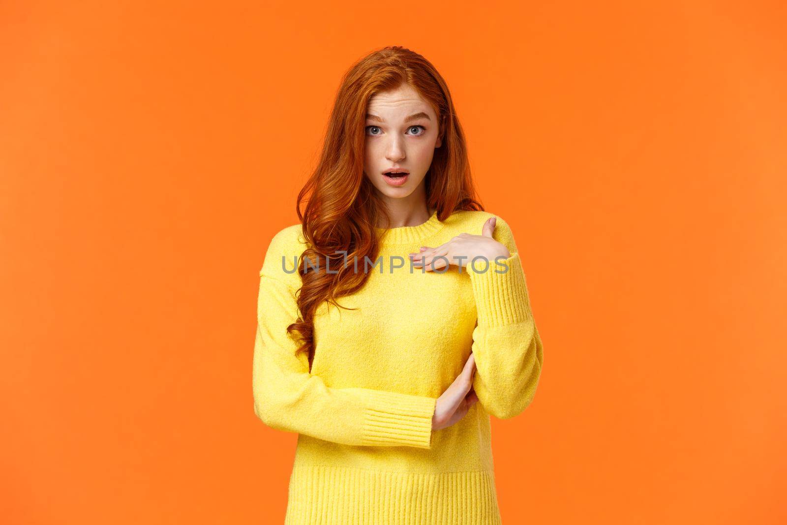 Who me. Frustrated and shocked, confused redhead woman accused, pointing herself and gasping stare astounded, feeling hurt person blame her, receive accusations, orange background.