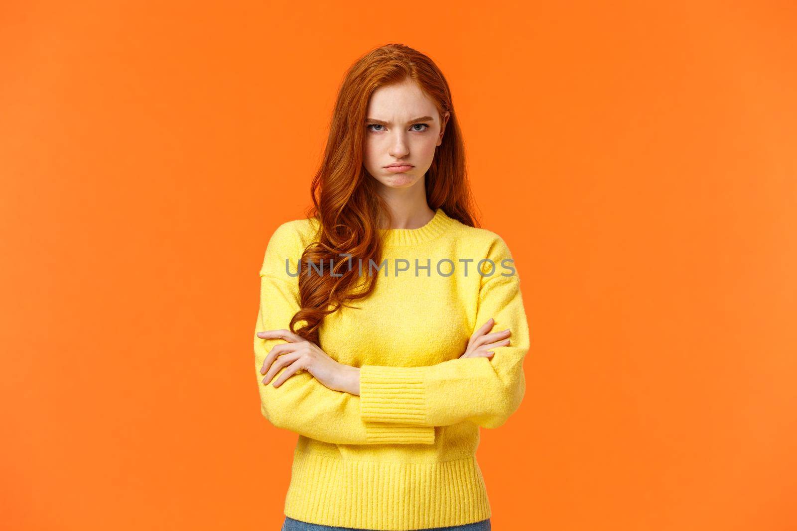 I am mad. Offended sulky cute and timid redhead curly girl, cross arms chest, sulking angry and tensed, frowning stare disappointed someone sad rude words, standing orange background insulted by Benzoix