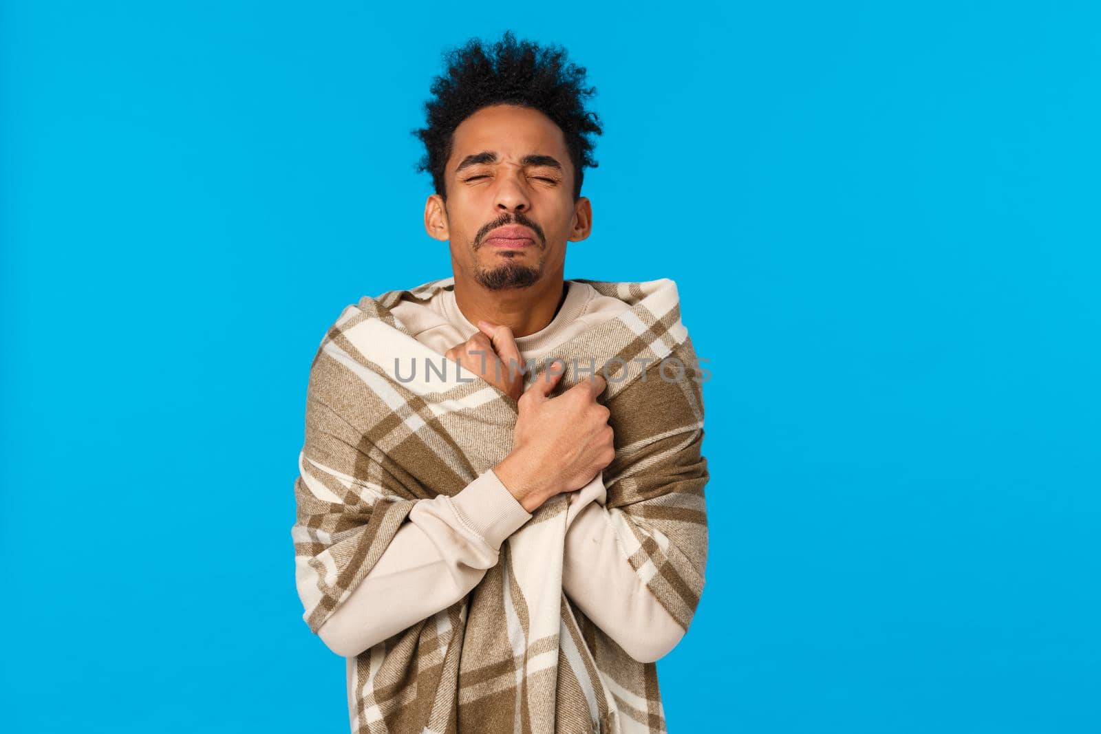 Wais-up portrait sick african american hipster guy with modern afro haircut, sneezing, have runny nose, wrap body in blanket get warm, caught cold during winter holidays, stay home blue background.