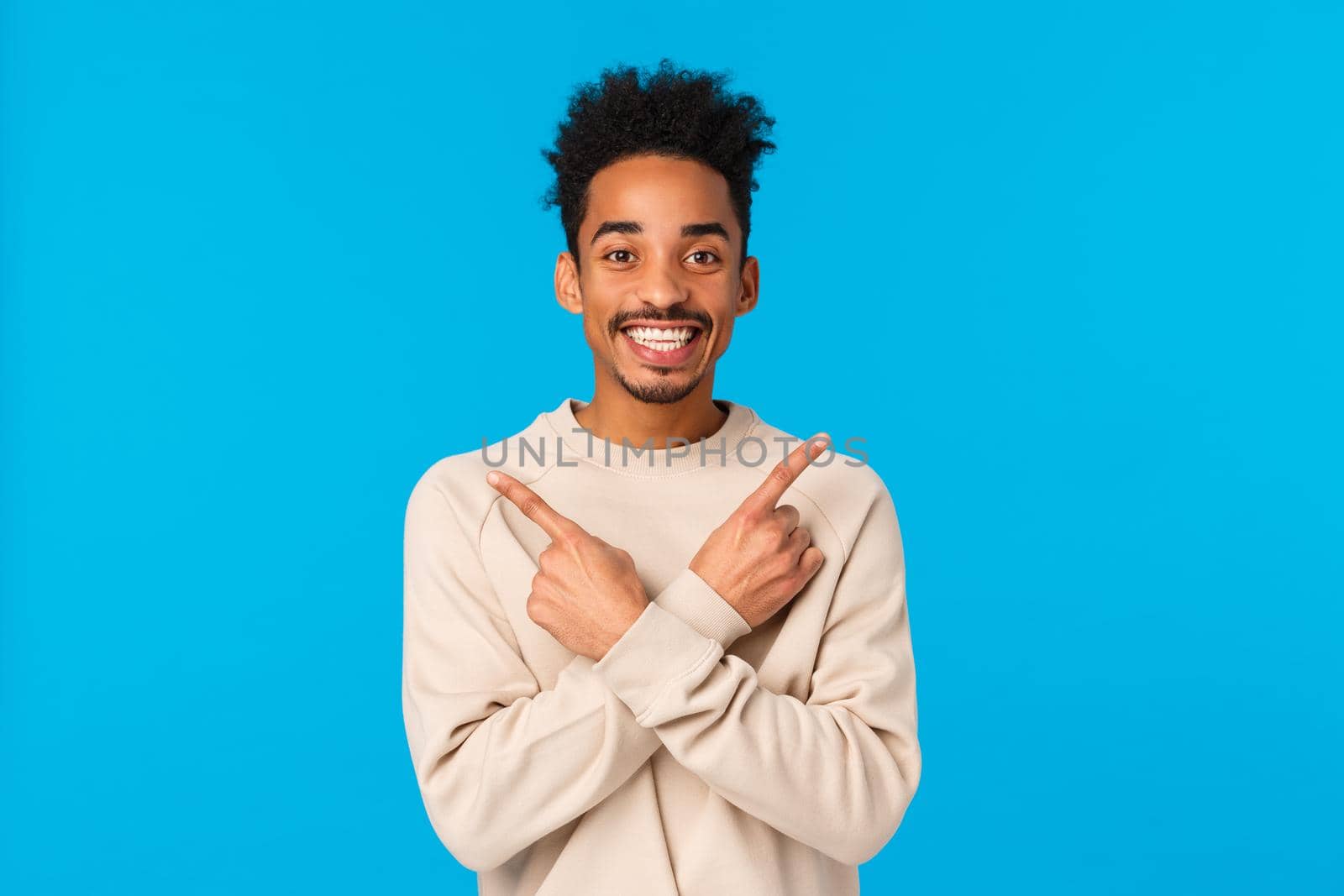 Handsome cheerful boyfriend cant wait celebrate holidays, asking friend opinion about two choices of gift, pointing sideways unsure, making decision, showing left and right products, smiling.