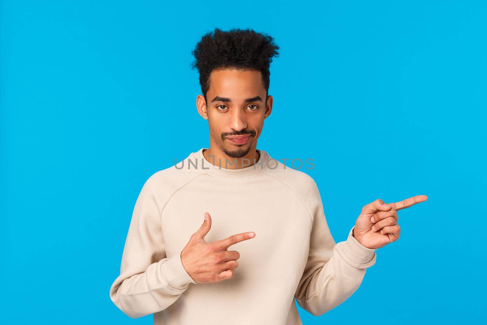 So lame, gosh. African-american good-looking man with moustache, afro haircut smirk skeptical looking with sarcastic expression, pointing right unsatisfied and unimpressed, blue background.
