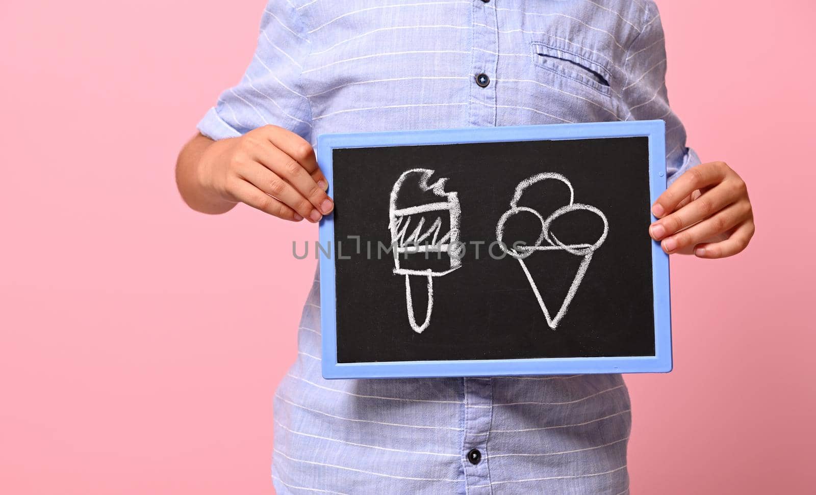 Cropped view of a boy hands holding a chalkboard with drawn ice cream against pink background with copy space. concepts