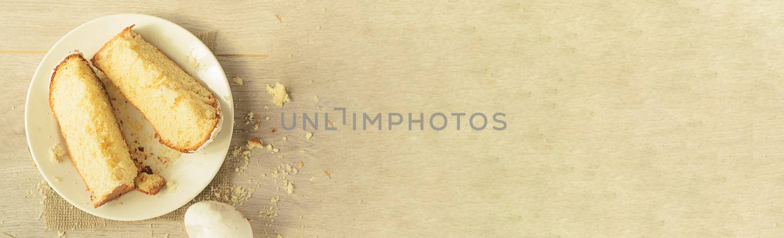 Top view, slices of sweet Easter cake on a plate and one egg on a light wooden background,copyspace.Easter concept.