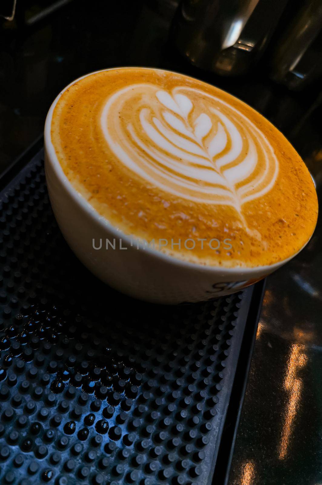 Tulip latte art on cafe latte on dark rubber mat by Wierzchu