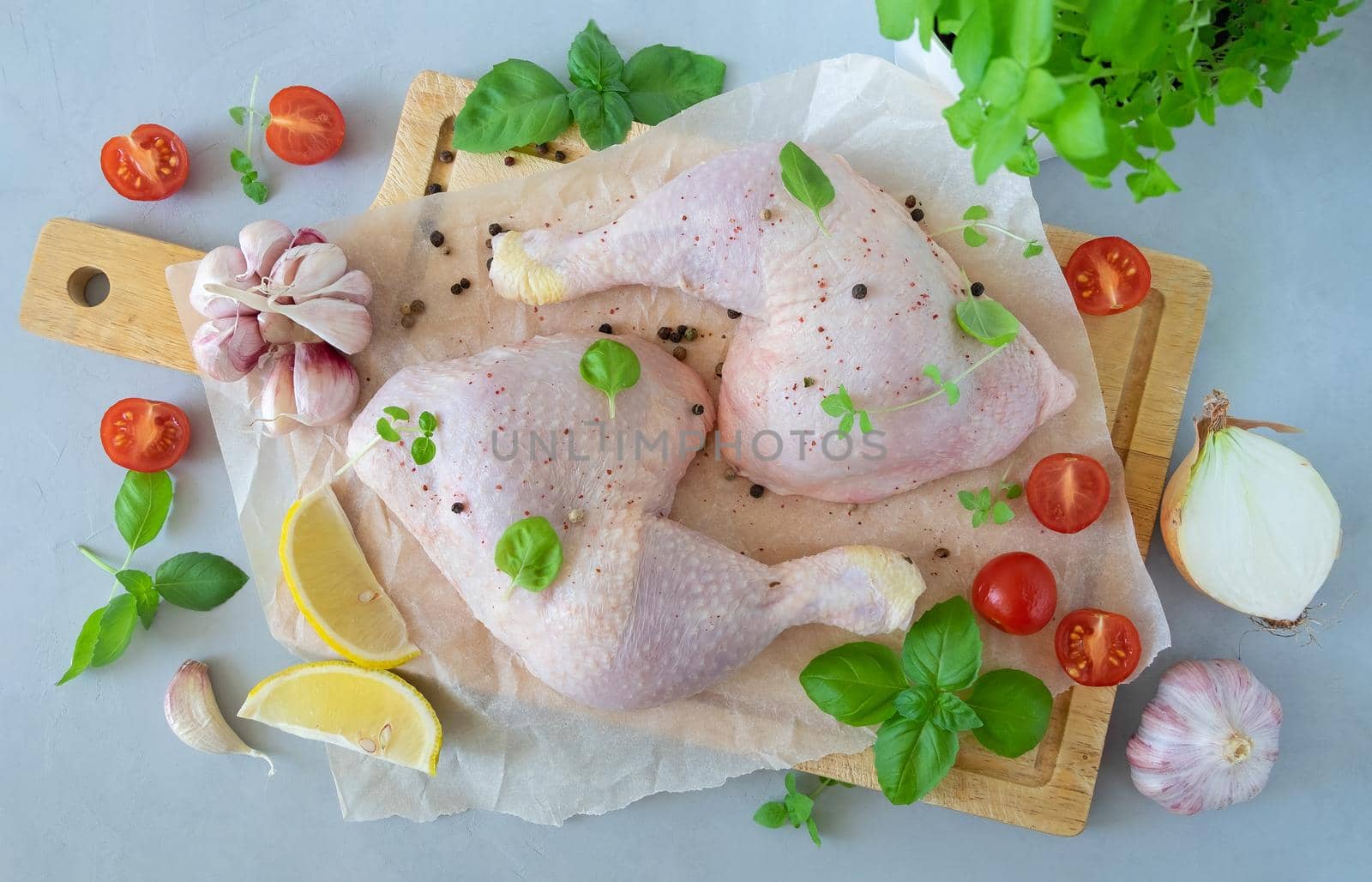 Close-up of chicken thighs with spices and kitchen herbs for cooking on a wooden cutting board. Horizontal orientation, selective focus, top view. Healthy food.