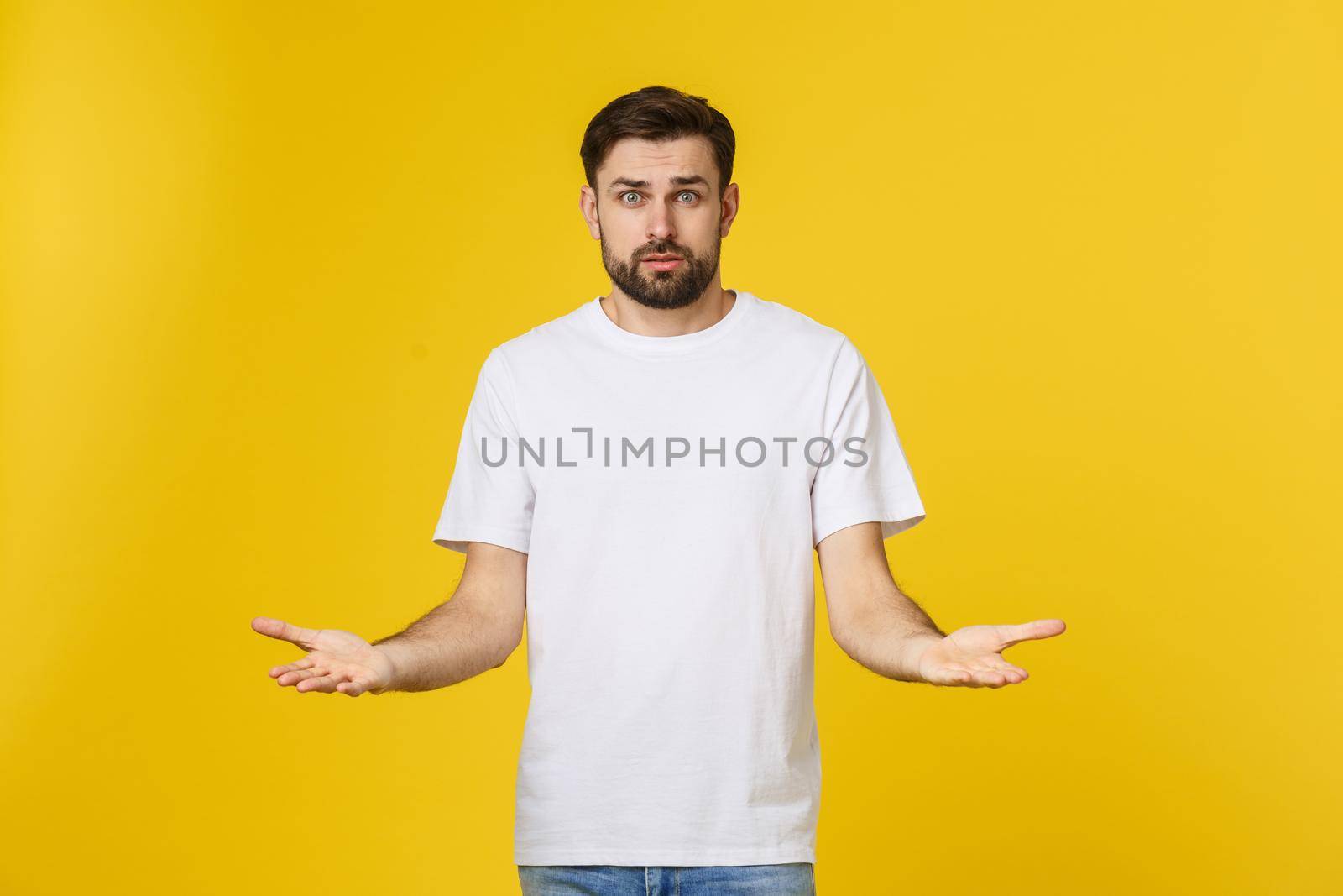 Portrait unhappy handsome man looking at camera on yellow background. by Benzoix
