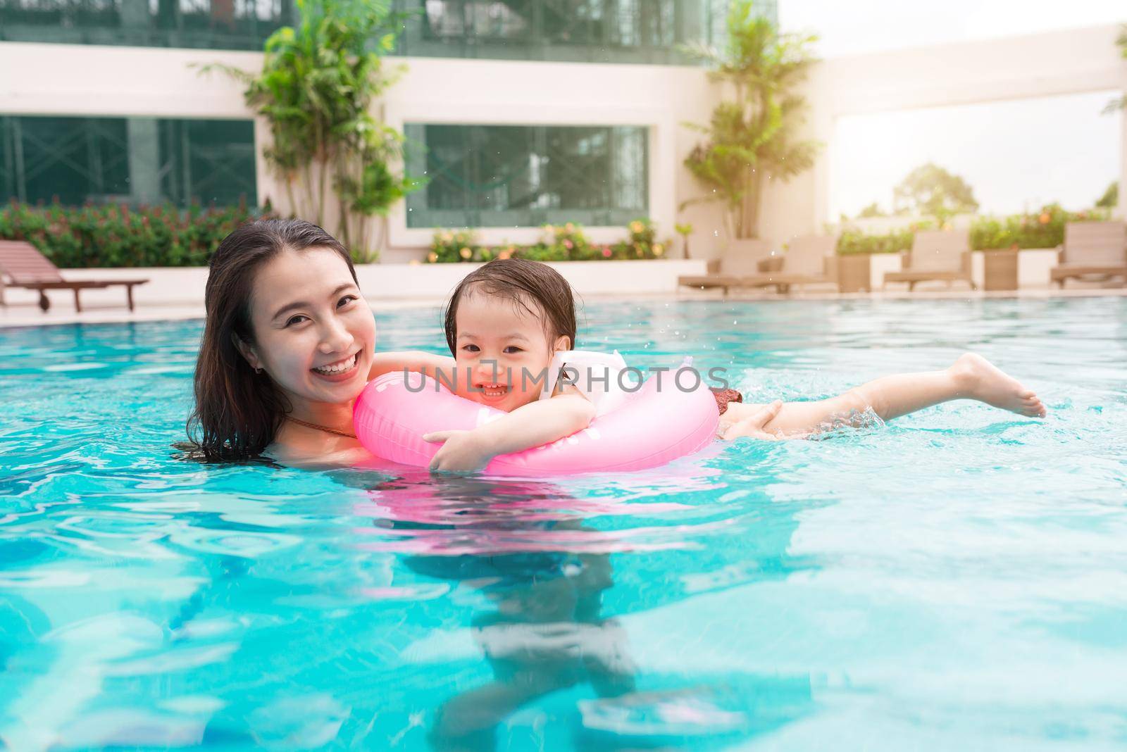 Mother and baby girl having fun in the pool. Summer holidays and vacation concept