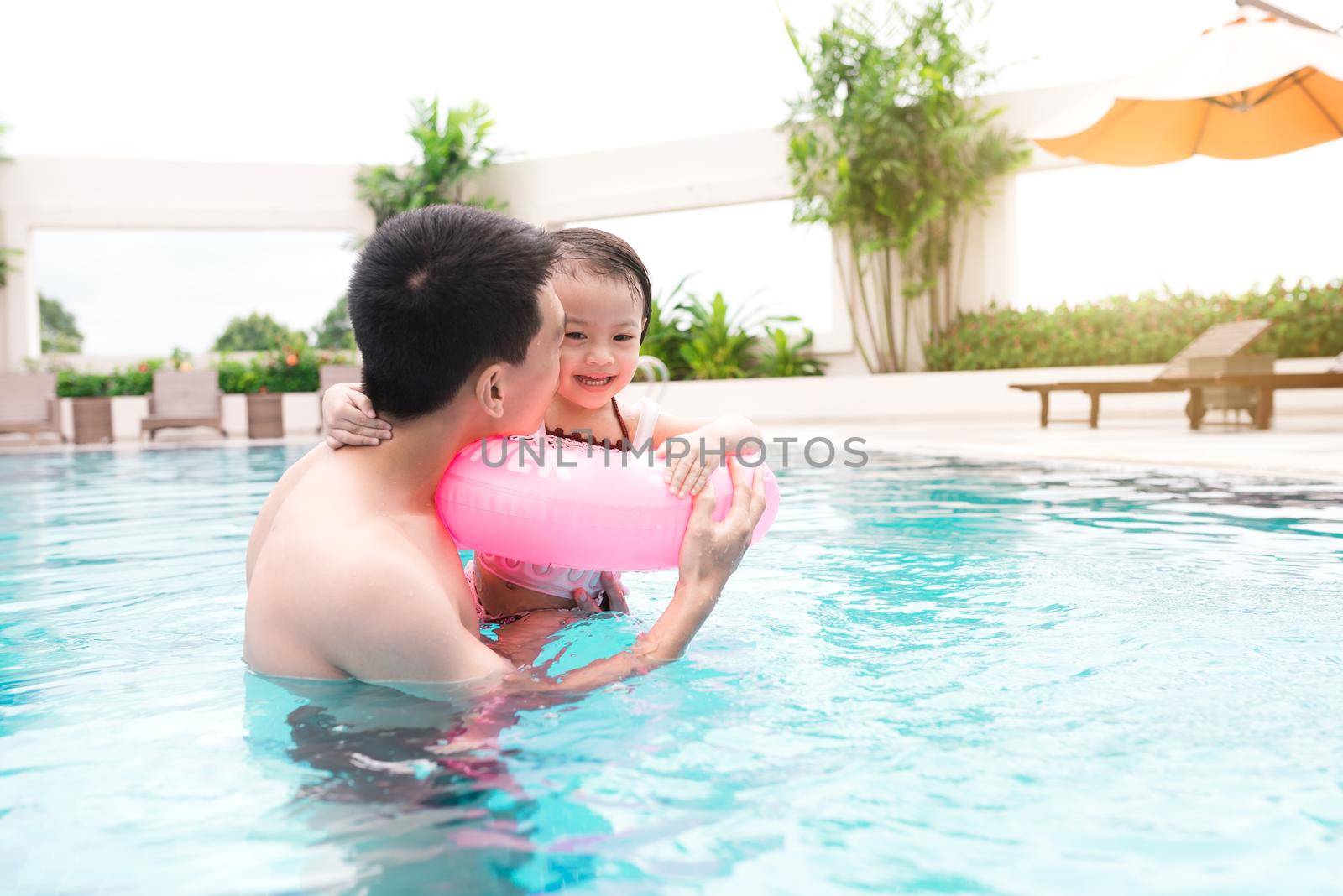 Father and daughter having fun in the pool. Summer holidays and vacation concept by makidotvn