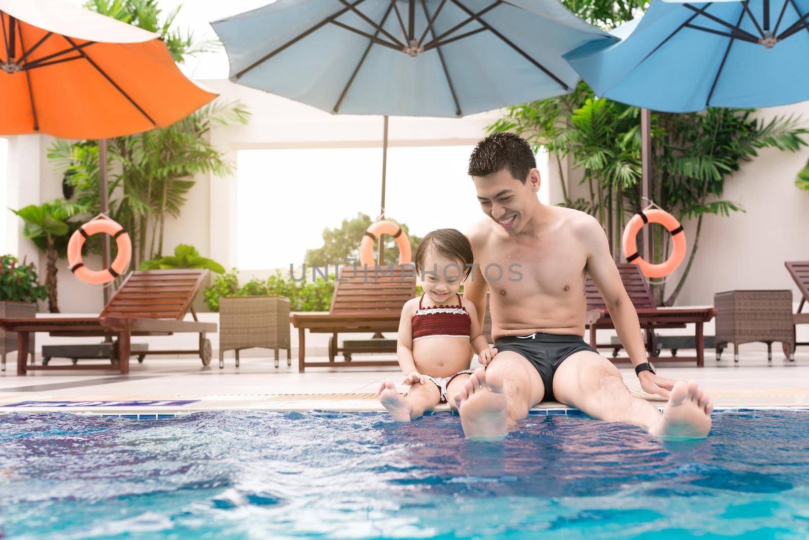 Father and daughter having fun in the pool. Summer holidays and vacation concept