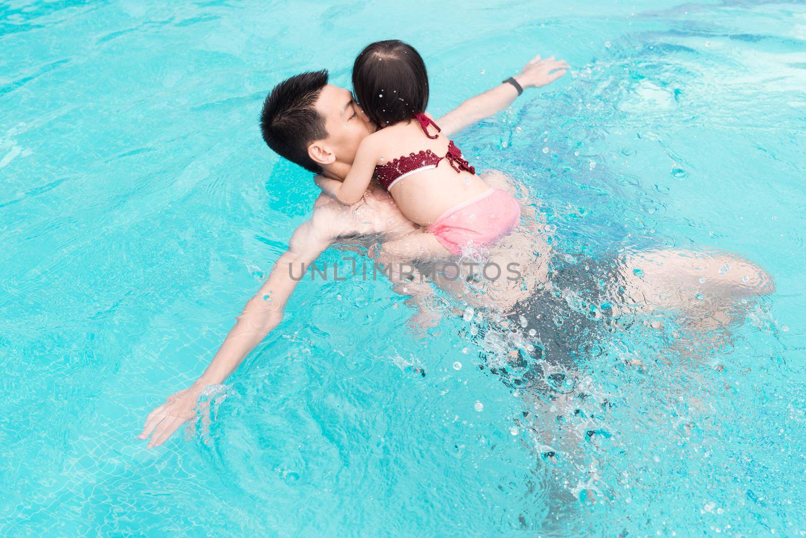 Father and daughter having fun in the pool. Summer holidays and vacation concept by makidotvn