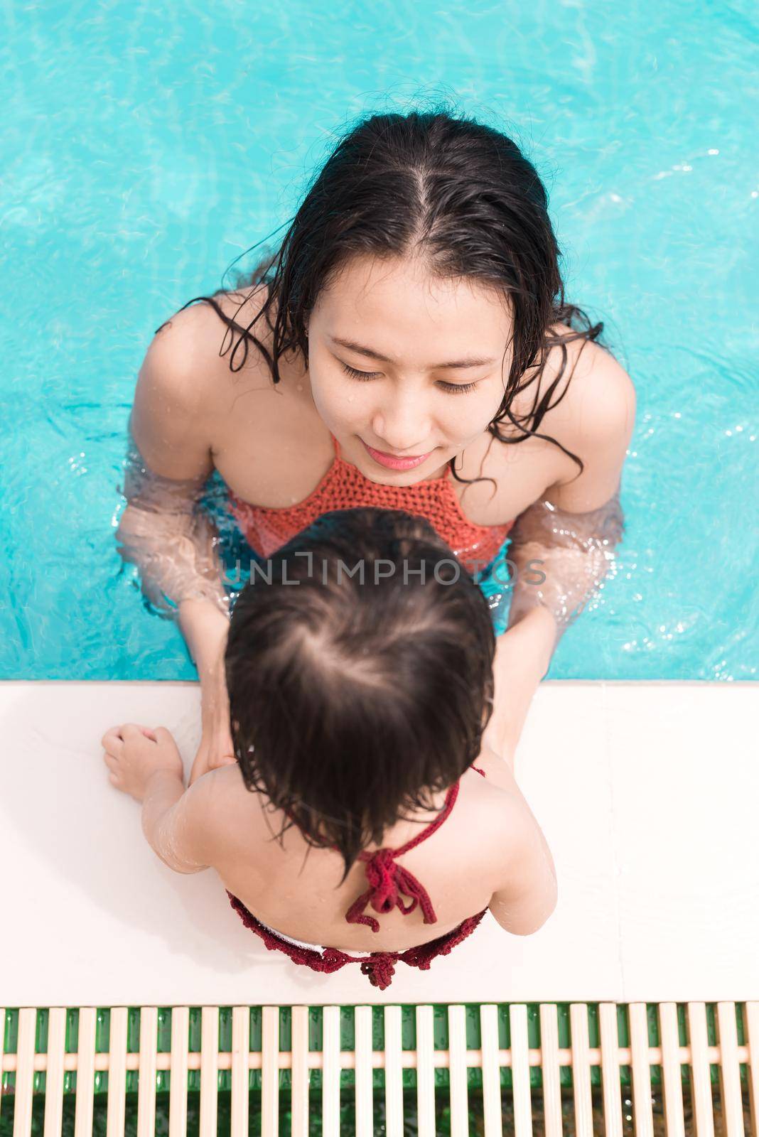 Mother and daughter having fun in the pool. Summer holidays and vacation concept