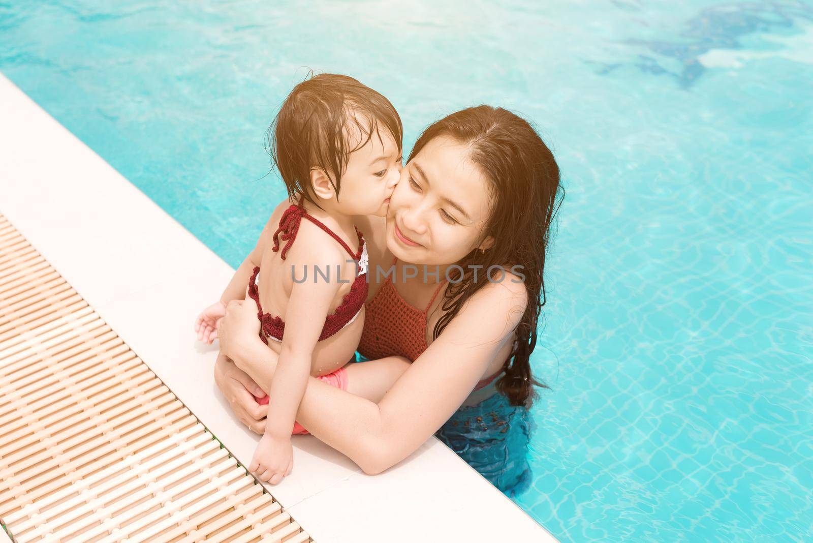 Mother and daughter having fun in the pool. Summer holidays and vacation concept by makidotvn