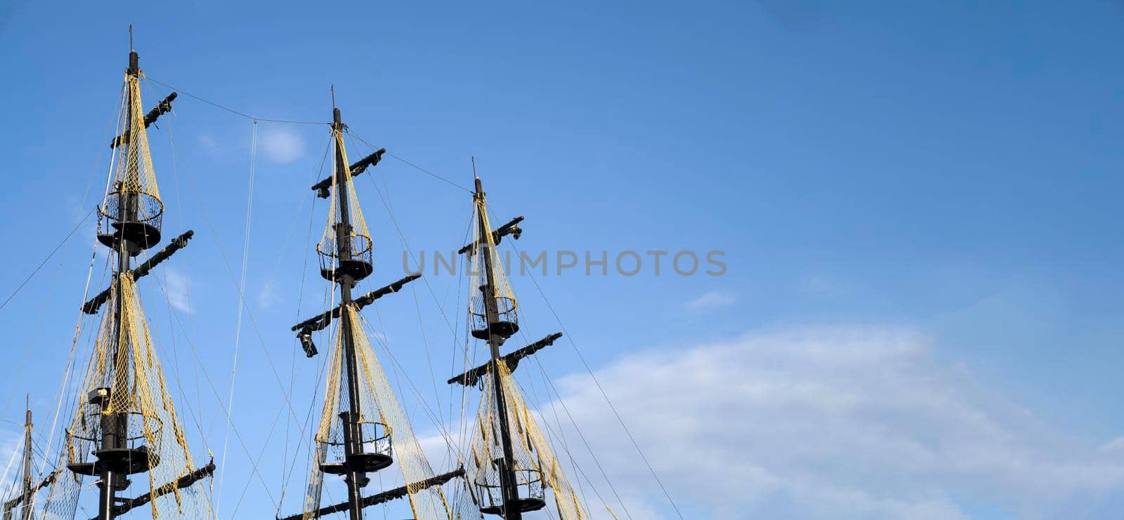 The masts of the ship on the background of the blue sky. The concept of travel and freedom. Copy space