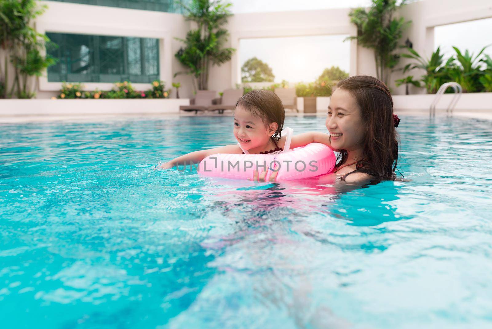 Mother and baby girl having fun in the pool. Summer holidays and vacation concept