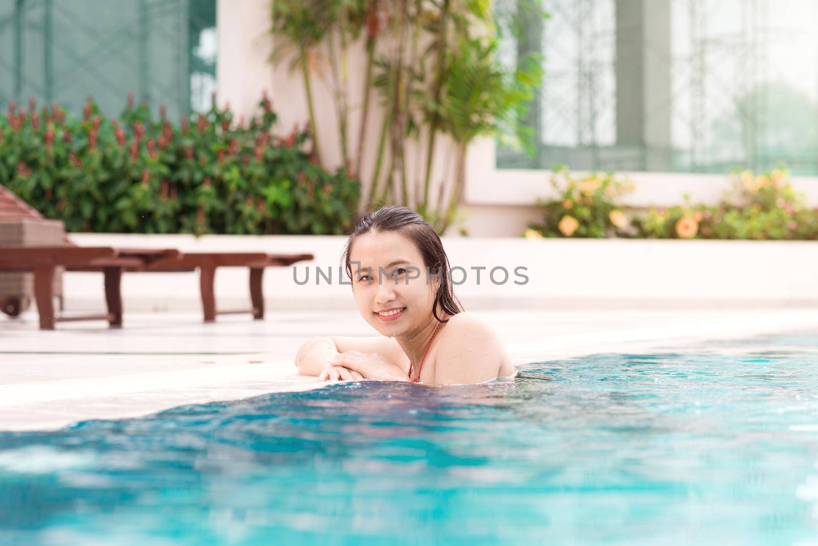 Beautiful asian woman smiling in a swimming pool by makidotvn