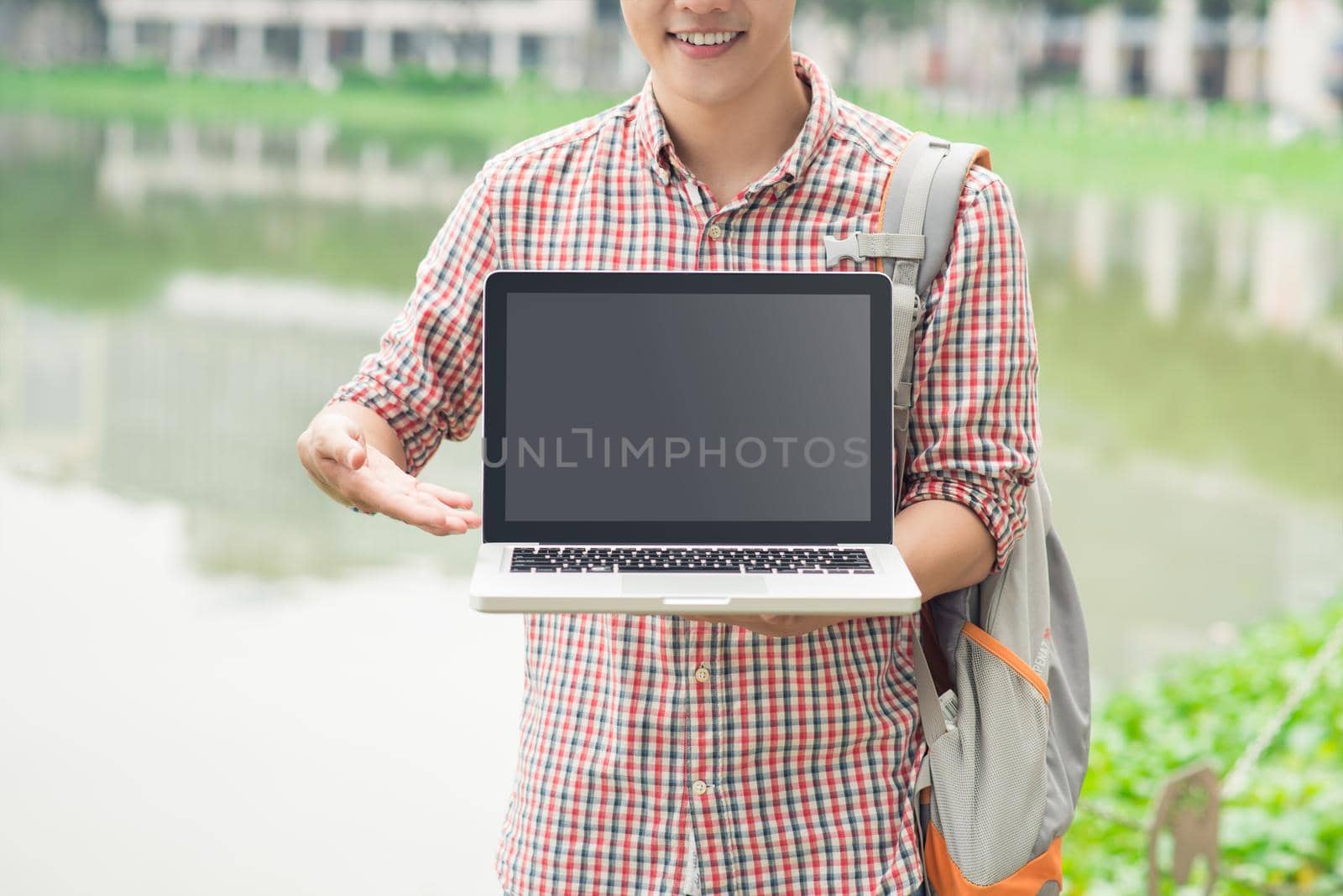 Male asian hand showing laptop screen outdoors by makidotvn