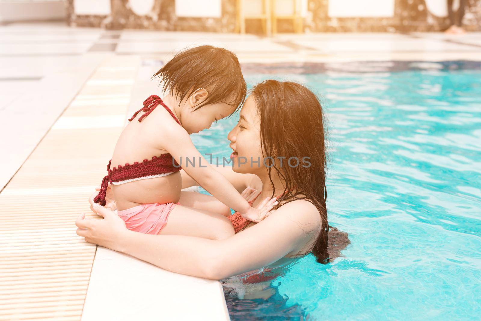 Mother and baby girl having fun in the pool. Summer holidays and vacation concept by makidotvn