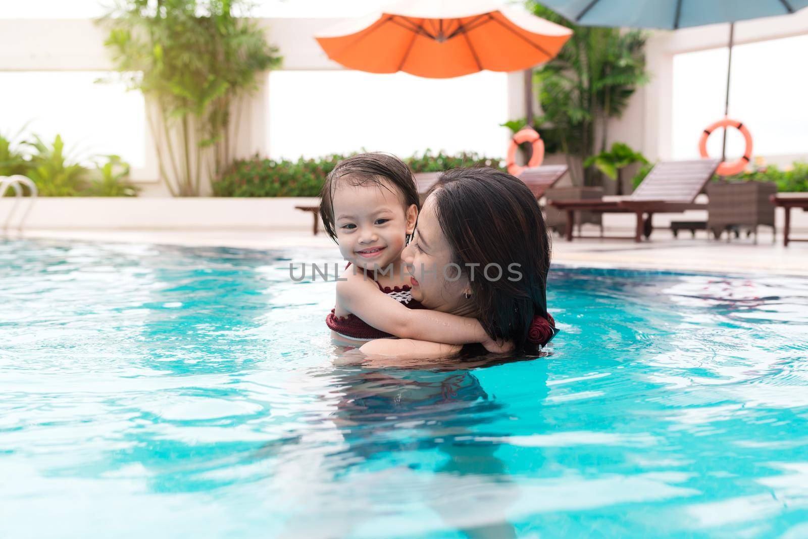 Mother and baby girl having fun in the pool. Summer holidays and vacation concept