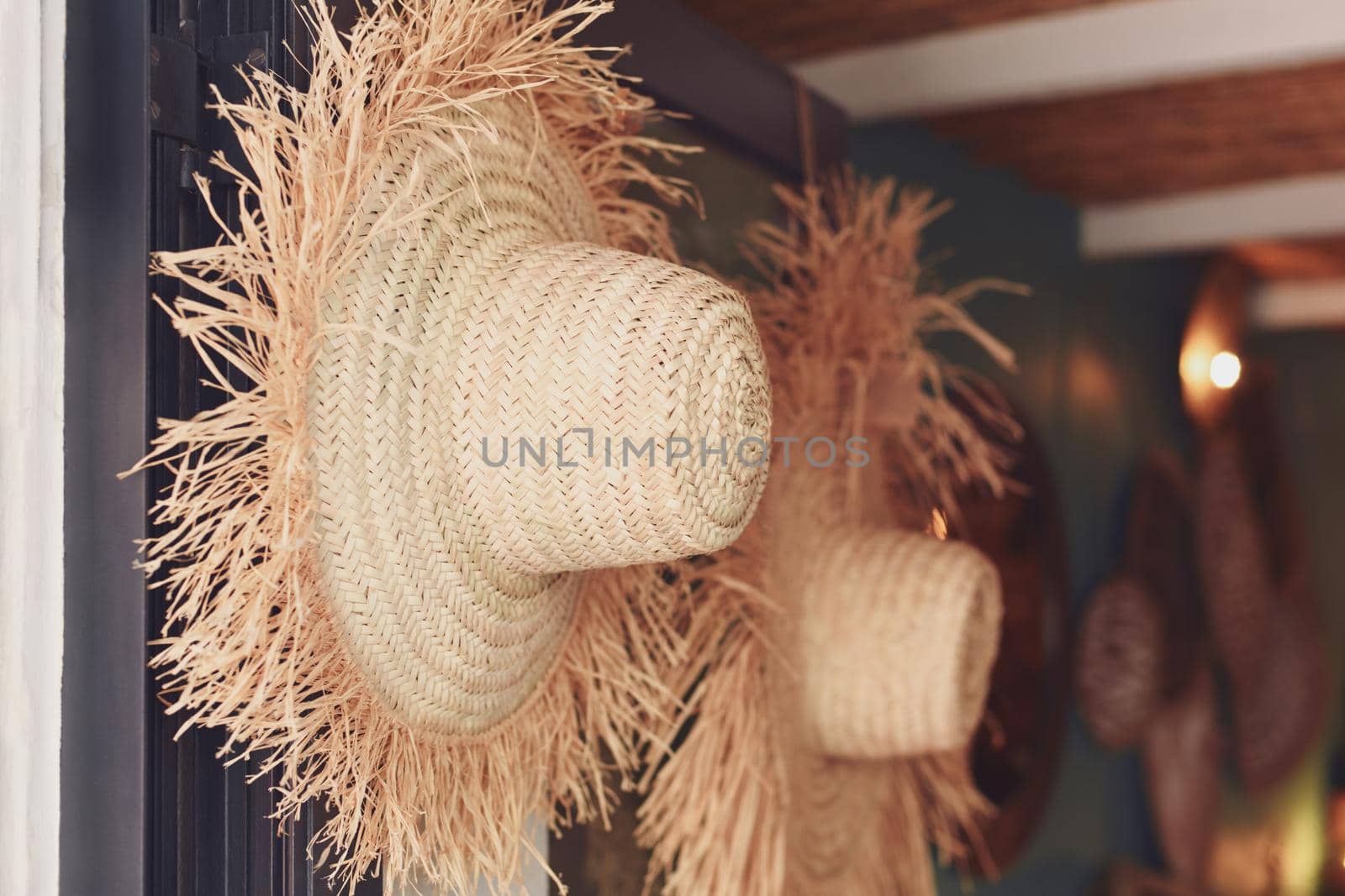 Handmade straw hats hanging in the store by Godi