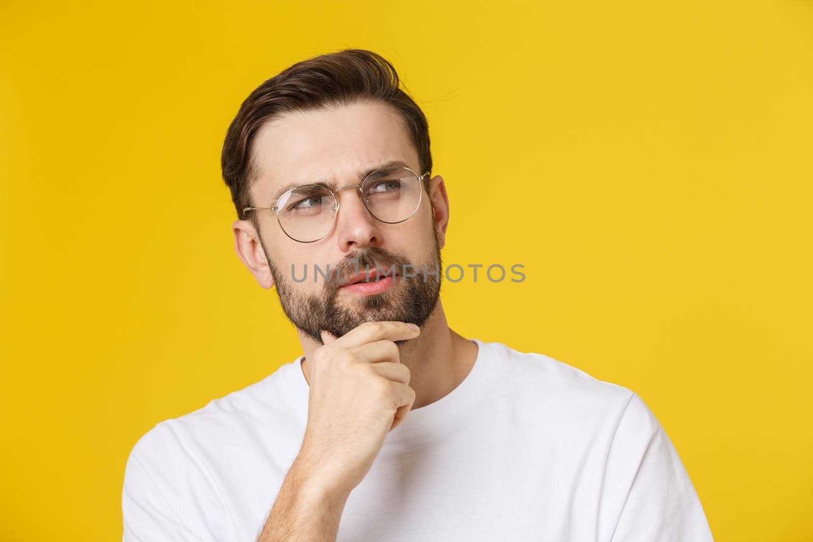 Thinking man isolated on yellow background. Closeup portrait of a casual young pensive man looking up at copyspace. Caucasian male model. by Benzoix