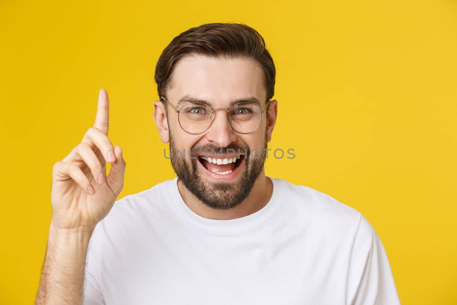 Young man looking at copyspace having a surprised or satisfied look isolated on yellow background