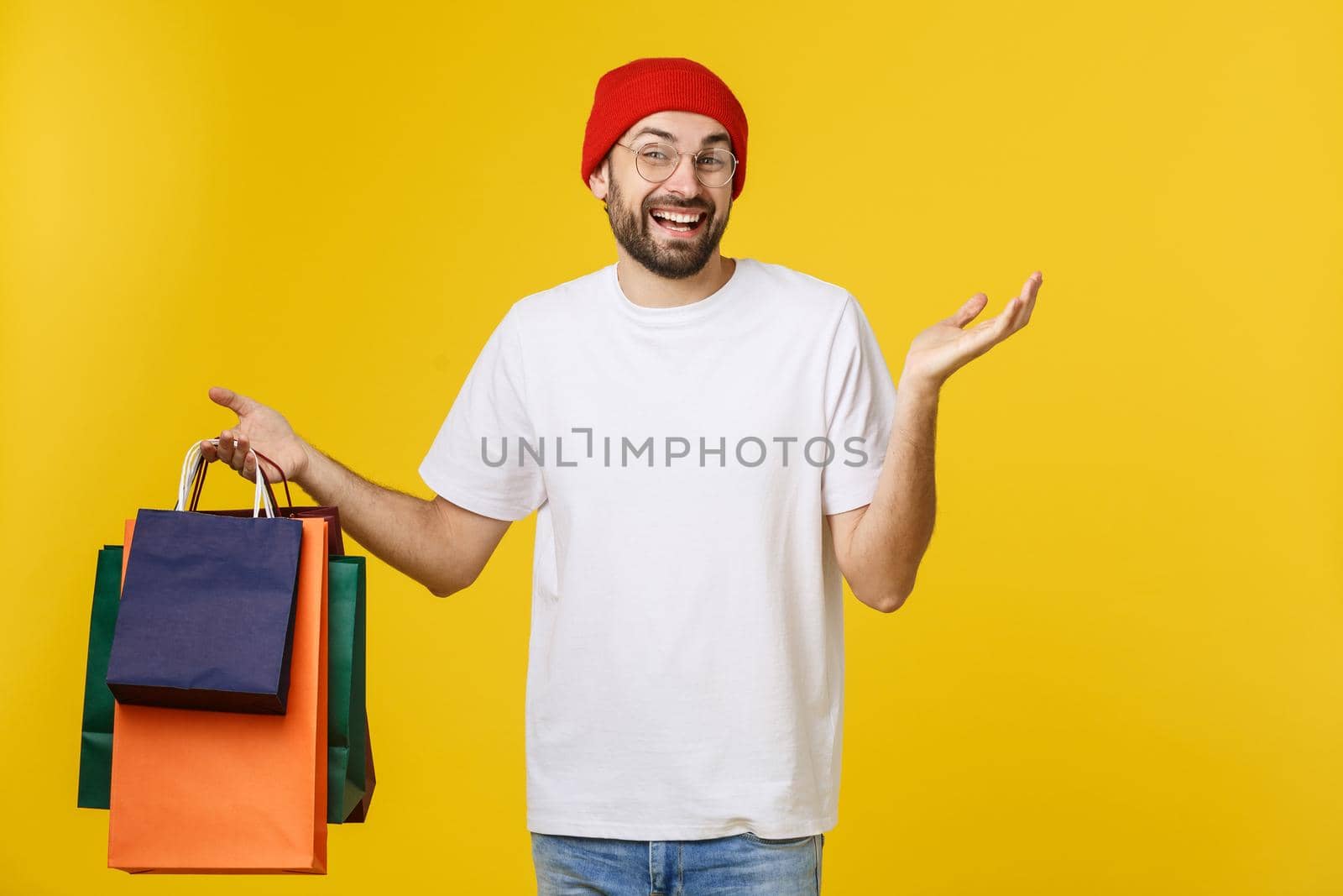 Bearded man with shopping bags with happy feeling isolated on yellow bacground.